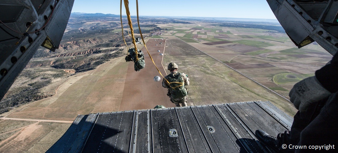 military personnel jumping out of the back of an aircraft for a parachute jump exercise