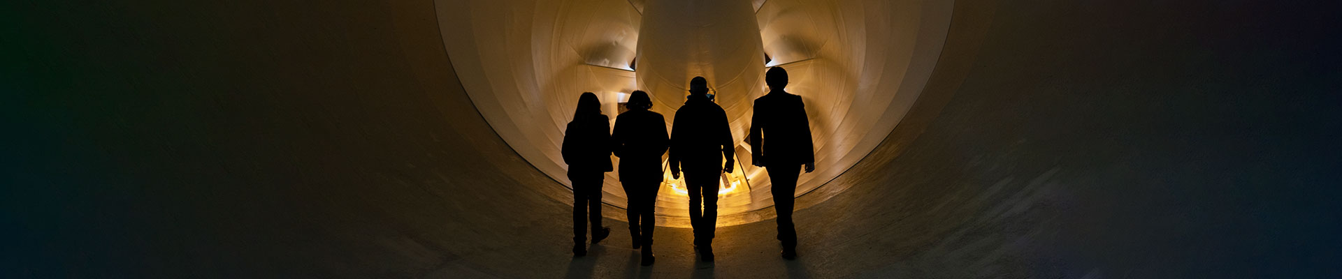 Four people standing in front of QinetiQ's 5 metre wind tunnel turbine