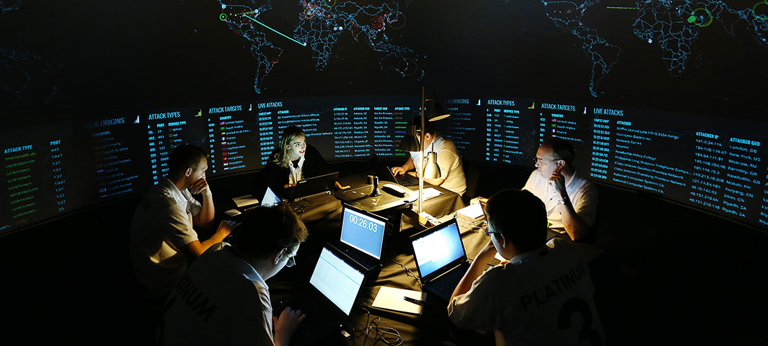 People gathered around computers in a room gathering intellignece to showcase our work with the Intelligence Community