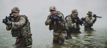 Military operations - soldiers advancing through water with rifles to shoulders