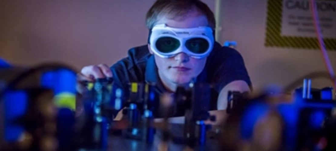 Man wearing goggles, carrying out a laser optic experiment